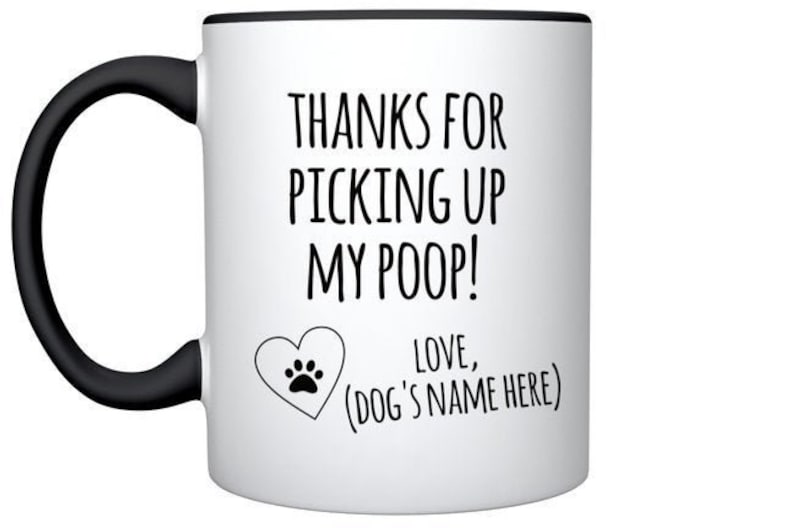 May include: White ceramic coffee mug with a black handle and rim. The mug has a black paw print heart and the text "THANKS FOR PICKING UP MY POOP! LOVE, (DOG'S NAME HERE)"