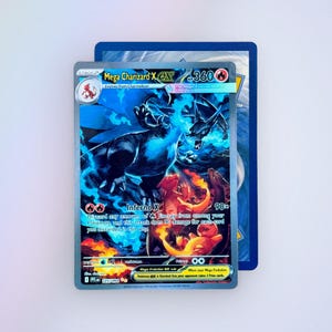 May include: A Mega Charizard X EX trading card featuring a dark blue dragon-like creature surrounded by blue flames and smaller orange fire-type creatures. The card displays the text Mega Charizard X EX, 360 HP, and Inferno X 90x.