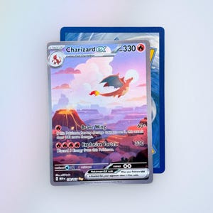May include: A Charizard ex trading card featuring a flying orange dragon-like creature above a volcanic landscape. The card displays 330 HP, Brave Wing and Explosive Vortex attacks, and the text 199/165. It is layered over a blue-backed card.