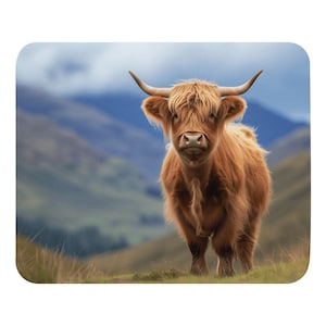 May include: A close-up of a Highland cow with long, reddish-brown fur and large horns. The cow is standing in a field with a blurred background of rolling hills.