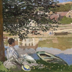 May include: A woman in a striped shirt sits on the bank of a river, looking out at the water. A small boat is in the water, and there are buildings and trees in the background.