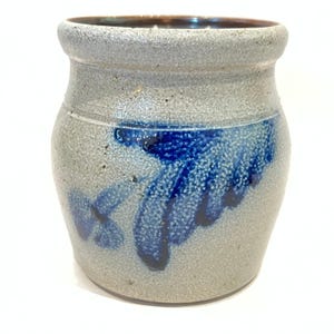 Puede incluir: Un tarro de gres con un acabado moteado gris claro y un diseño abstracto azul oscuro. El borde es de color marrón más oscuro. Este recipiente de estilo vintage es adecuado para la cocina o la decoración del hogar.