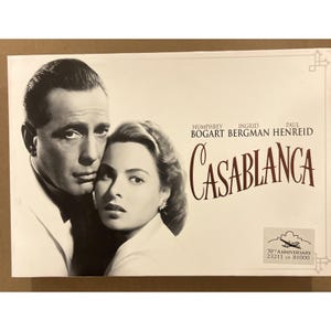 May include: Casablanca movie poster featuring Humphrey Bogart and Ingrid Bergman. The title "Casablanca" is in a stylized font. The poster commemorates the 70th anniversary of the film.