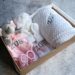 Pink Baby Gift Set featuring a personalized baby blanket, adorable baby elephant comforter, personalized baby bib, cozy baby knitted hat, soft baby mittens, and cute baby knitted booties.