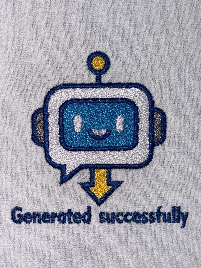 May include: Embroidered design featuring a blue robot with a speech bubble and a yellow arrow, accompanied by the text "Generated successfully" in navy blue. The robot has a smiling face and a yellow antenna. The design is on a light grey fabric.