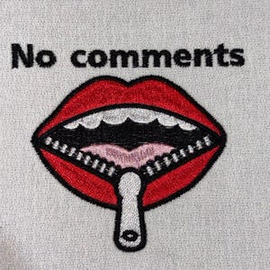 Könnte beinhalten: Gestickter Aufnäher mit einem roten Mund mit Reißverschluss und den Worten "No comments" in Schwarz. Das Design befindet sich auf einem hellgrauen Stoff und setzt ein klares Statement.