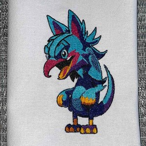 May include: Embroidered design of a blue, purple, and yellow cartoon bird with a long beak and a spiky crest. The bird is standing on two legs with yellow feet.