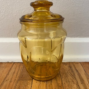 May include: Amber glass jar with a lid. The jar has a textured, rounded design.