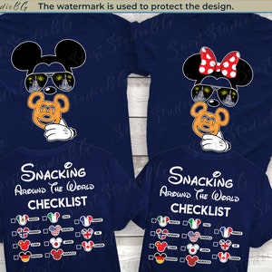 May include: Two navy blue t-shirts featuring a Mickey Mouse and Minnie Mouse design. The shirts include a checklist with the text "Snacking Around the World Checklist" and a list of countries with flags and Mickey Mouse heads.