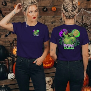 Puede incluir: Una camiseta de manga corta de color morado oscuro con un peque&ntilde;o gr&aacute;fico verde de Oogie Boogie en el pecho izquierdo con el texto CUSTOM. La parte trasera muestra un gr&aacute;fico grande de Oogie Boogie, una telara&ntilde;a y el texto OOGIE BOOGIE BASH 2026.