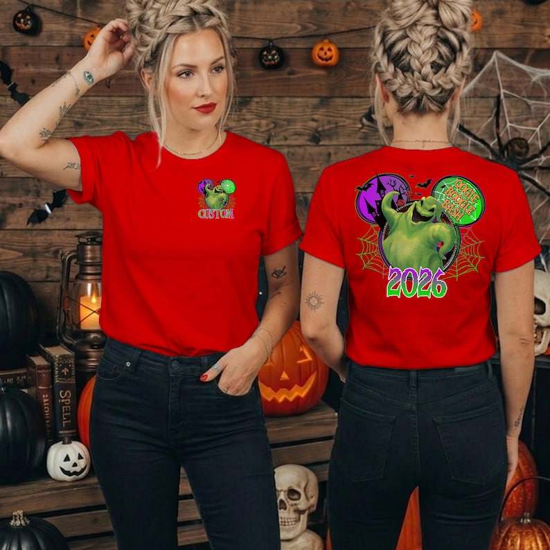 Puede incluir: Una camiseta roja de manga corta con un peque&ntilde;o gr&aacute;fico verde del personaje Oogie Boogie en el pecho izquierdo. La parte posterior muestra un gran gr&aacute;fico circular de Oogie Boogie, una casa encantada, murci&eacute;lagos y el texto Oogie Boogie 2026.