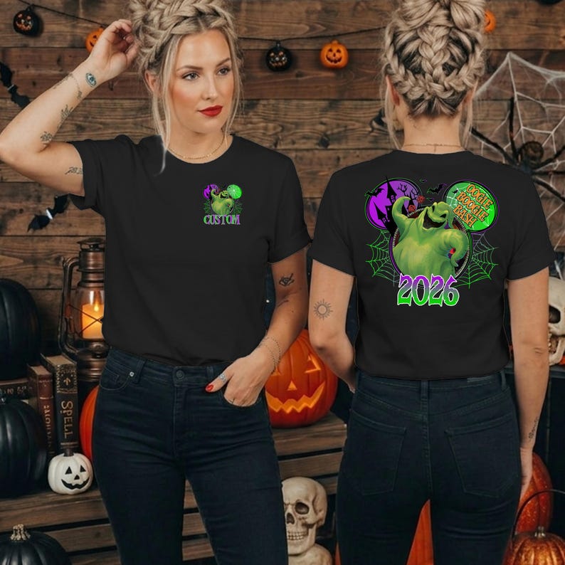 Puede incluir: Una camiseta negra de manga corta con un peque&ntilde;o gr&aacute;fico verde de Oogie Boogie en el pecho con la palabra CUSTOM. La parte trasera muestra un gran gr&aacute;fico verde de Oogie Boogie, una casa encantada morada, telara&ntilde;as y el texto OOGIE BOOGIE BASH 2026.