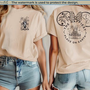 May include: Beige t-shirt with a black graphic on the front featuring a castle, Minnie Mouse, and the name "Sophia." The back of the shirt has a design with the text "The Happiest Place on Earth."