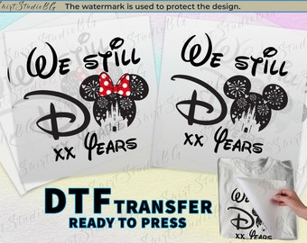 Könnte beinhalten: Ein schwarz-weißes Design für ein T-Shirt mit Mickey-Maus-Ohren mit Feuerwerk und einem Schloss im Inneren. Der Text "We Still Do XX Years" ist im Design enthalten.
