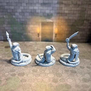 May include: Three unpainted grey miniature figurines of snake-like creatures with human torsos. Each figure stands on a circular stone-textured base. One holds a spear, one holds a curved blade, and one holds a sword and a shield.