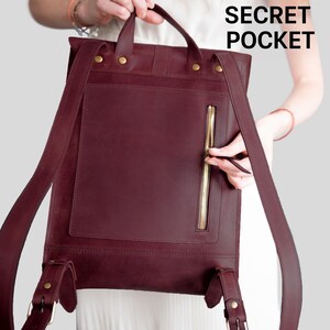 A person is holding a burgundy leather backpack with a zipper pocket, and the text "SECRET POCKET" is visible.