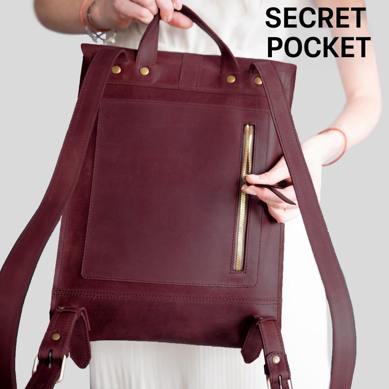 A person is holding a burgundy leather backpack with a zipper pocket, and the text "SECRET POCKET" is visible.