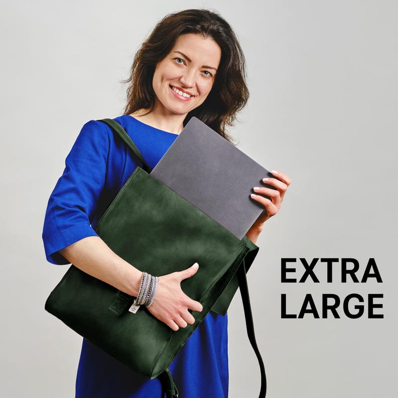 A woman in a blue dress is smiling and holding a large green bag, with a laptop inside.