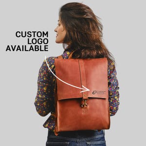 A woman with long brown hair is wearing a brown leather backpack, and there is text indicating that custom logos are available.