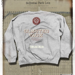 Może przedstawiać: Szara bluza z napisem "OLMSTED VAUX & Company" w stylu vintage. Bluza ma okrągłe logo z tyłu i mniejszy obraz logo w prawym dolnym rogu. Projekt nawiązuje do odzieży w stylu retro.