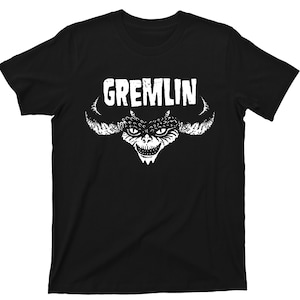 May include: Black t-shirt with a white graphic of a creature with the word "GREMLIN" above it.
