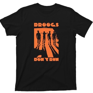 May include: Black t-shirt with an orange graphic of four figures walking in a row with the text "DROOGS DON'T RUN".