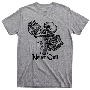 May include: A grey t-shirt featuring a black and white illustration of a skeleton drinking from a beer mug. The text "Never Quit" is printed below the illustration.