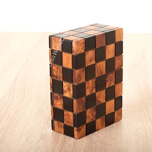 Peut inclure: Une boîte en bois avec un motif de damier en bois clair et foncé. La boîte est faite de petits carrés disposés en damier.
