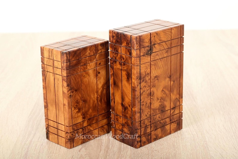 May include: Two rectangular wooden boxes with a natural brown wood grain pattern. Each box features a grid of vertical and horizontal grooves carved into the surface, creating a segmented appearance. The text MoroccanWoodCraft is visible.