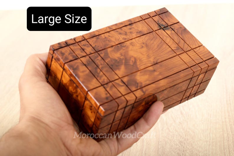 May include: A rectangular wooden box with a polished finish and a distinct burl wood grain pattern. The surface features a grid of incised lines creating a geometric design. A black label in the upper left corner displays the text Large Size.