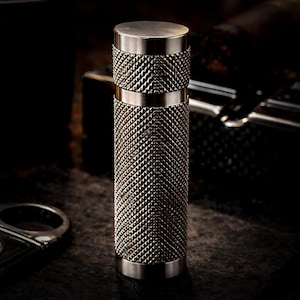 Op de afbeelding: Een set van drie keramische mokken met een gespikkelde, matte afwerking. De mokken zijn in crème, lichtgrijs en donkergrijs. Elke mok heeft een eenvoudig, minimalistisch ontwerp.