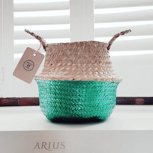 May include: A woven basket with a natural brown top and a bright green bottom. The basket has two handles and a small tag that says "Woven & True".