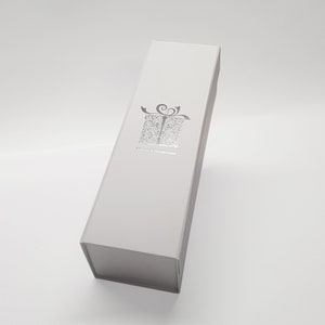 May include: White gift box with a silver embossed design of a present with a bow and the text "Happy Christmas".