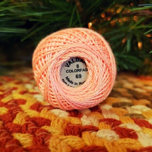 May include: A pink ball of yarn with a label that reads "VALD 8 COLORFAS 69 Made in Rom."