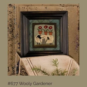 May include: Framed artwork featuring two sheep watering three potted red flowers. The artwork is in a black frame and is titled "#677 Wooly Gardener". The artwork is displayed on a shelf with greenery.