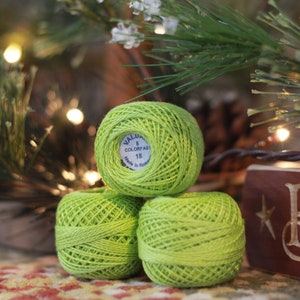 May include: Three green balls of yarn with a white label that reads "Valdani Colorfast 18 Made in France".