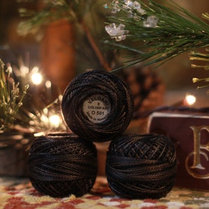 May include: Three spools of black embroidery floss, each with a label that reads "Valdani 8 Colorfast 0 501 Made in Romania".