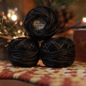 May include: Three balls of black and brown embroidery floss with a label that reads "Valdani 8 Colorfast 0 531 Made in Italy"