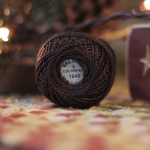 May include: A brown ball of embroidery floss with a white label that reads "Wald 8 Colorfas 1645"