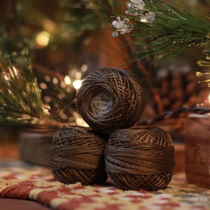 May include: Three brown spools of thread stacked on top of each other. The top spool has a white label with the text "COLUMBUS 0196".