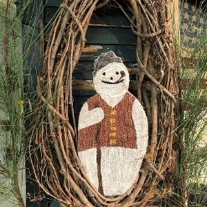May include: A whimsical snowman decoration made of white fabric, wearing a brown vest and a gray hat, set within a rustic twig wreath. The snowman has a smiling face and is displayed against a weathered wooden background.