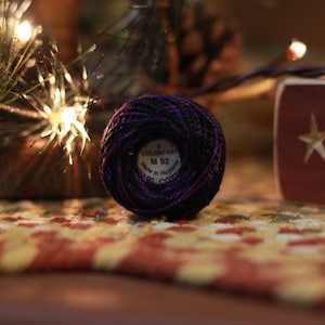 May include: A spool of purple and black embroidery thread with the label "COLORFAST M 92 Made in Romania" on the side.