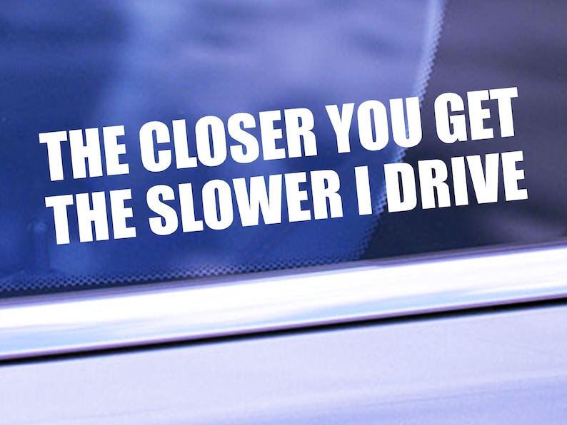 May include: A white vinyl sticker on a blue car window that reads "The closer you get the slower I drive."