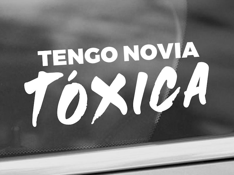 K&ouml;nnte beinhalten: Wei&szlig;er Vinyl-Aufkleber mit dem Text "TENGO NOVIA T&Oacute;XICA" in einer fetten, stilisierten Schrift.