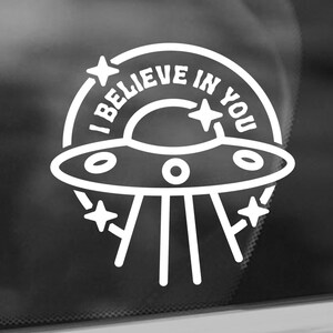 May include: White vinyl sticker with a UFO and the text "I believe in you" with stars around the UFO.