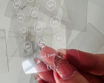 May include: A clear plastic card with a white outline of a circle around the text "$10", "$15", "$20", and "$25". The card also has the text "VALENTINE'S" and "HALLOWEEN" printed on it. The card has the text "Total $200" printed on it.