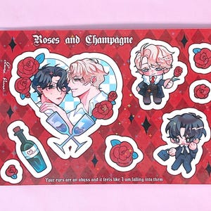 May include: A sticker sheet with a red background and a diamond pattern. The sheet features illustrations of two men, roses, champagne glasses, and small cartoon figures. Text reads "Roses and Champagne" and "Your eyes are an abyss and it feels like I am falling into them."