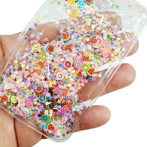 May include: A clear plastic pouch filled with colorful glitter and small fruit-shaped charms. The pouch is designed to be a phone case or a decorative item.