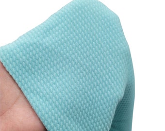 May include: A close-up of a light blue textured fabric. The fabric has a waffle-like texture.