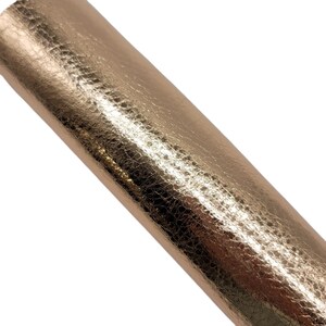 May include: A close-up of a sheet of rose gold metallic faux leather with a textured, pebbled surface.